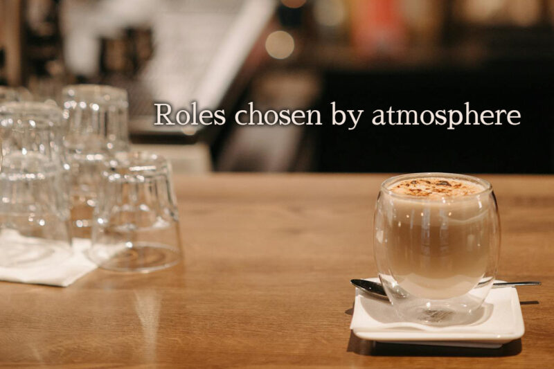 木製カウンターに置かれた二重ガラスのカフェラテと積まれたグラス